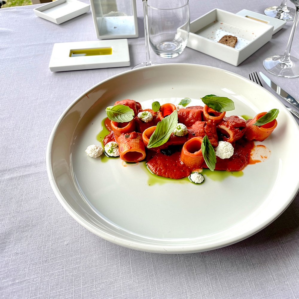 Piatto di pasta al pomodoro e basilico su una tavola apparecchiata di bianco